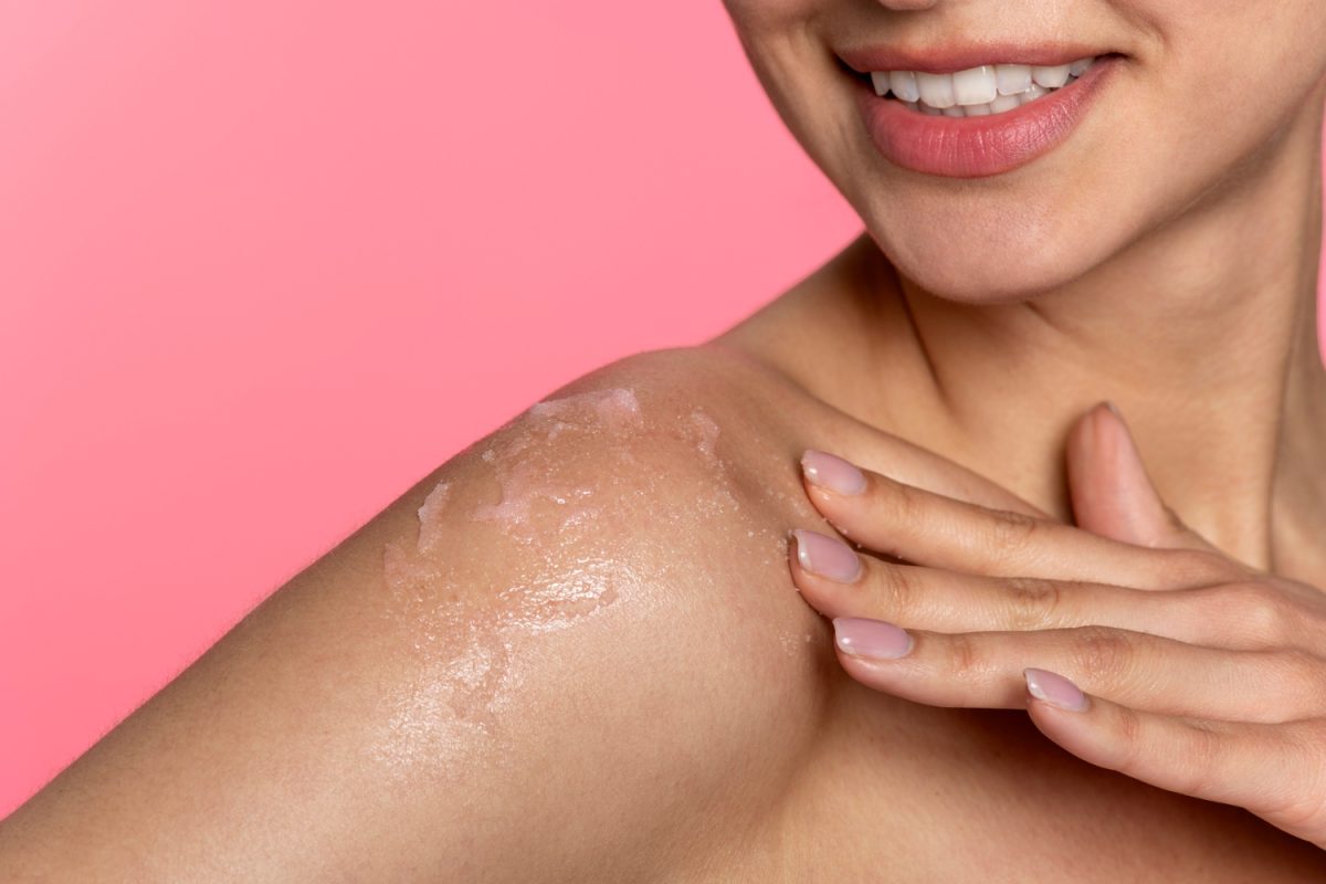 Vue latérale smiley femme appliquant une crème pour le corps